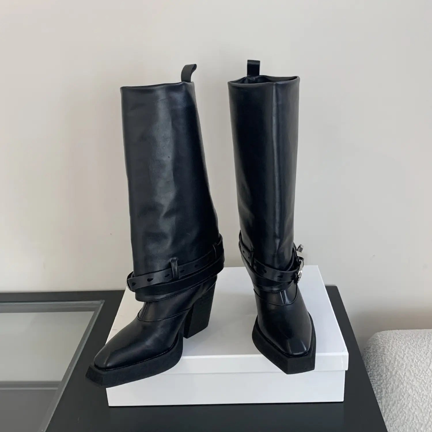 black leather knee-high winter pointed toe boots with a chunky block heel and decorative buckle straps