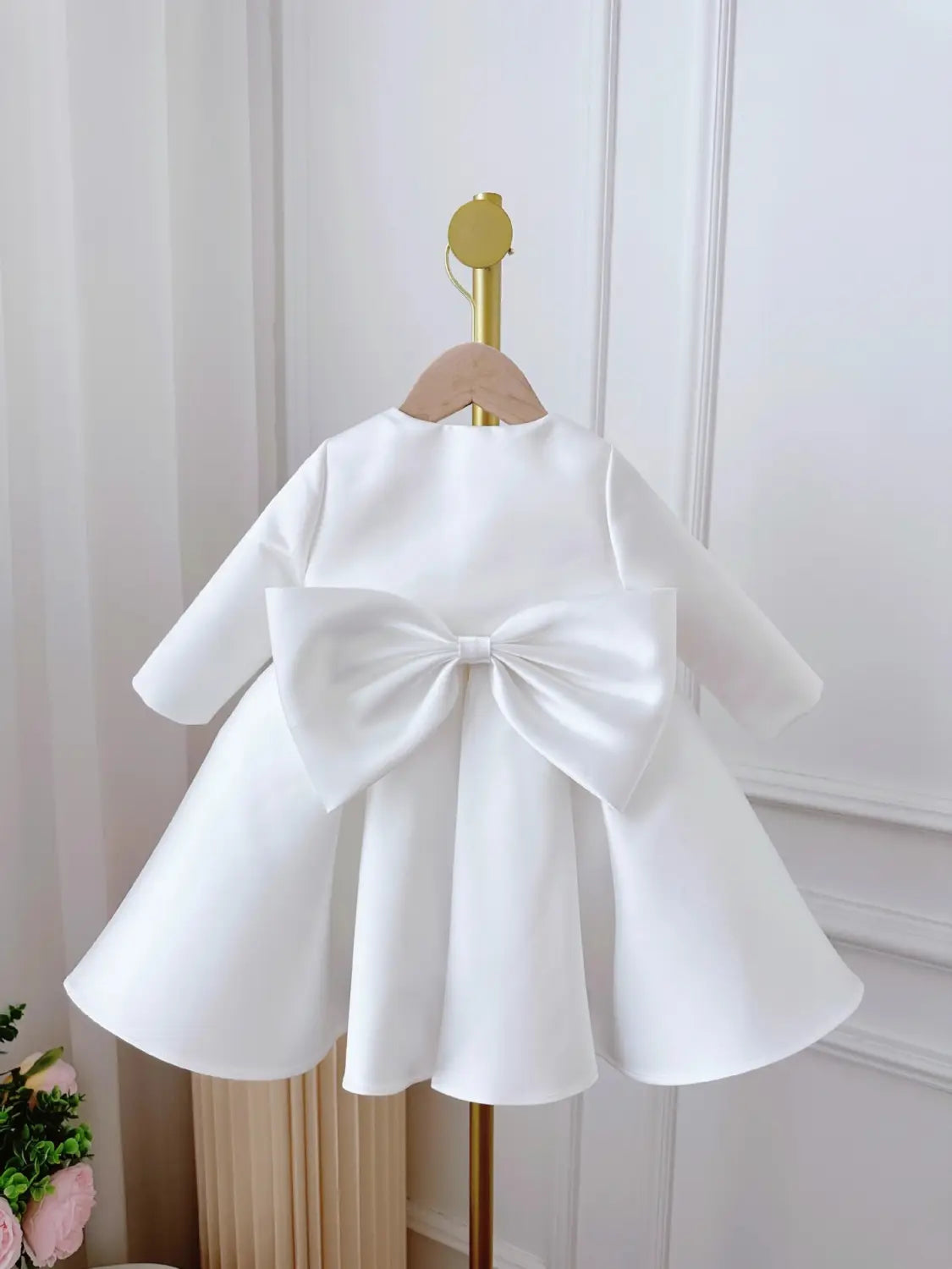 white satin long sleeve baby dress white classic style shown from the back with a large bow detail in a dress white classic design