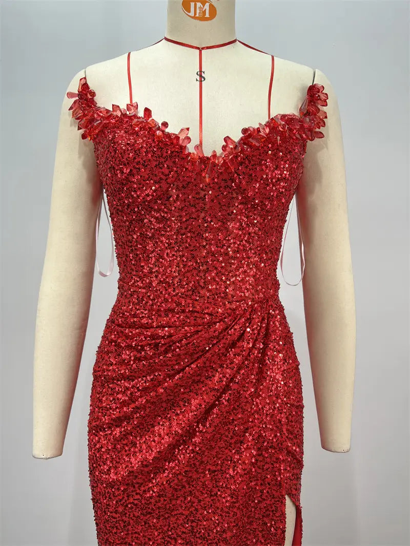 a dazzling red paillette tube high slit evening gown with floral embellishments on the shoulder straps and a side slit