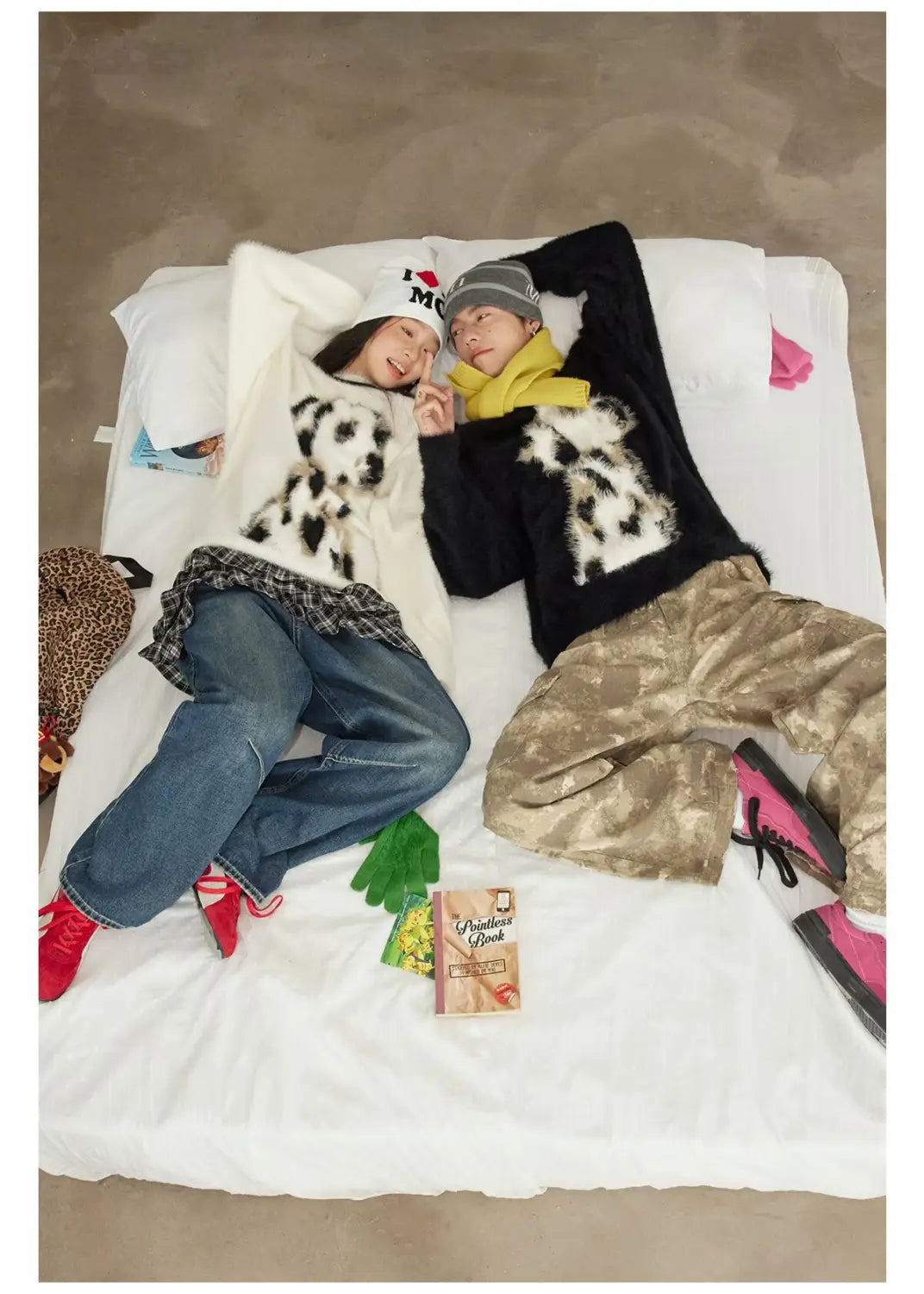 two individuals wearing matching black and white dalmatian puppy jacquard mink cashmere knitted sweaters paired with blue jeans and red shoes and camouflage pants with pink sneakers