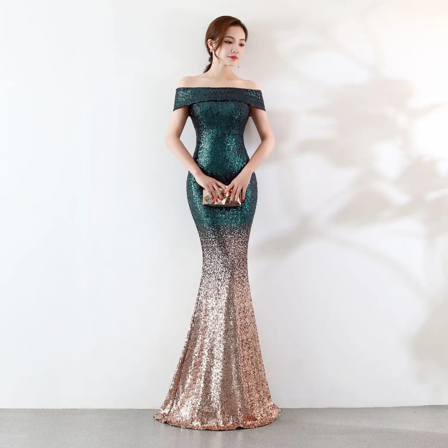 A shimmering mermaid-style birthday party dress with an off-the-shoulder neckline featuring a gradient of deep emerald green to rose gold sequins designed as a party dress slimming host gown.