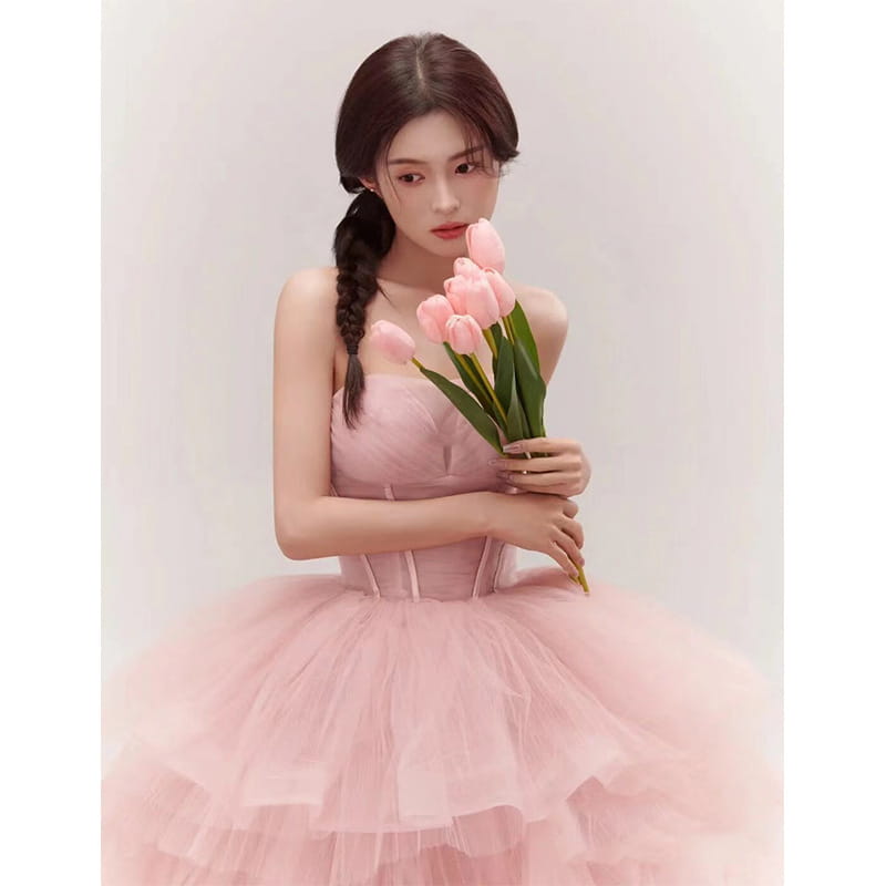 A soft pink tiered tulle dress fairy temperament main featuring a structured bodice and layered ruffles made from temperament main yarn.
