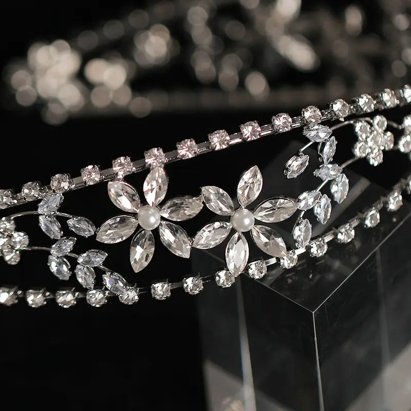 a delicate silver bridal crown headdress adorned with sparkling clear rhinestones and intricate floral crystals each flower centered with a small pearl