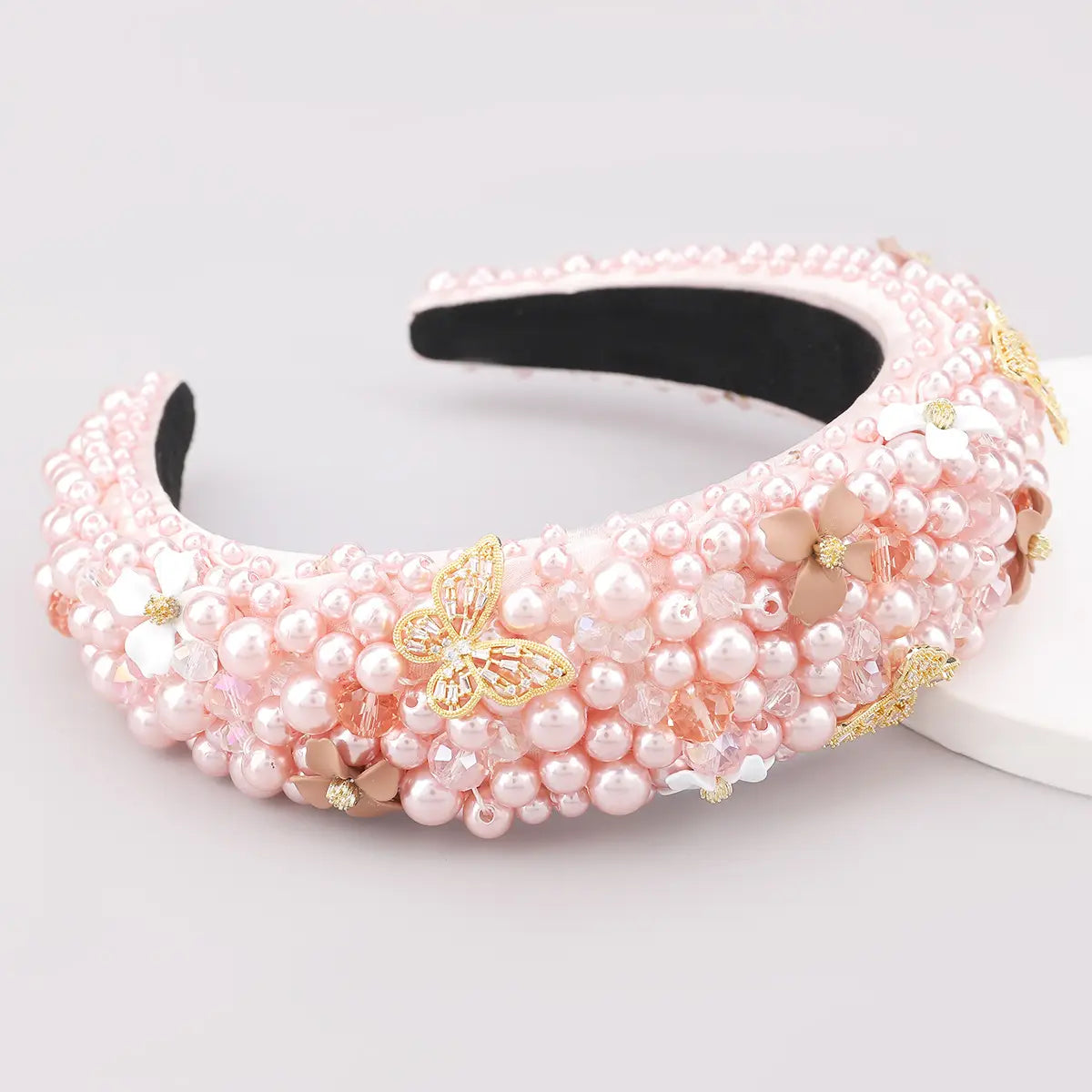 A delicate pink pearl headband with gold butterfly and floral embellishments designed as fashionable personality hair accessories using hair accessories fabric.