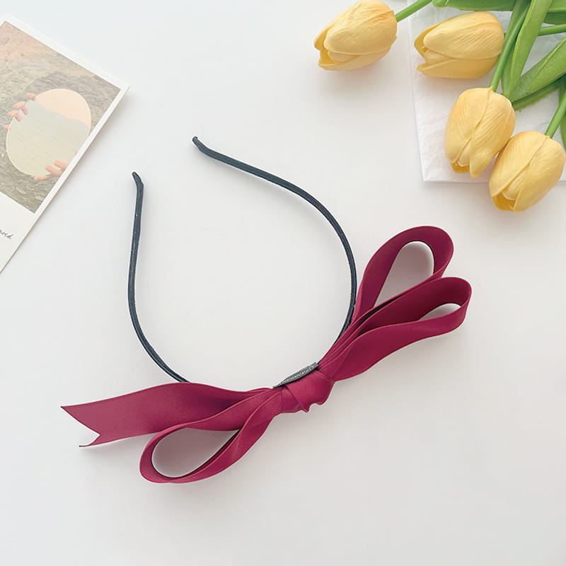 A black bow headband featuring a large plush maroon french satin bow for women.
