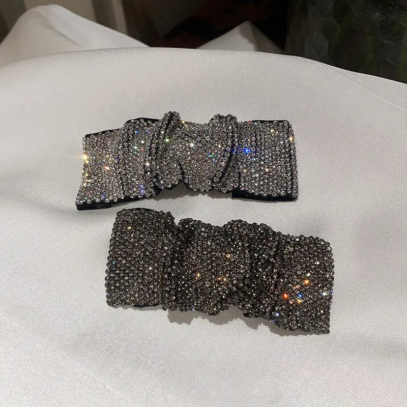 Two sparkling pleated bb clip bow hair clips in silver and dark gray with hot rhinestone details.