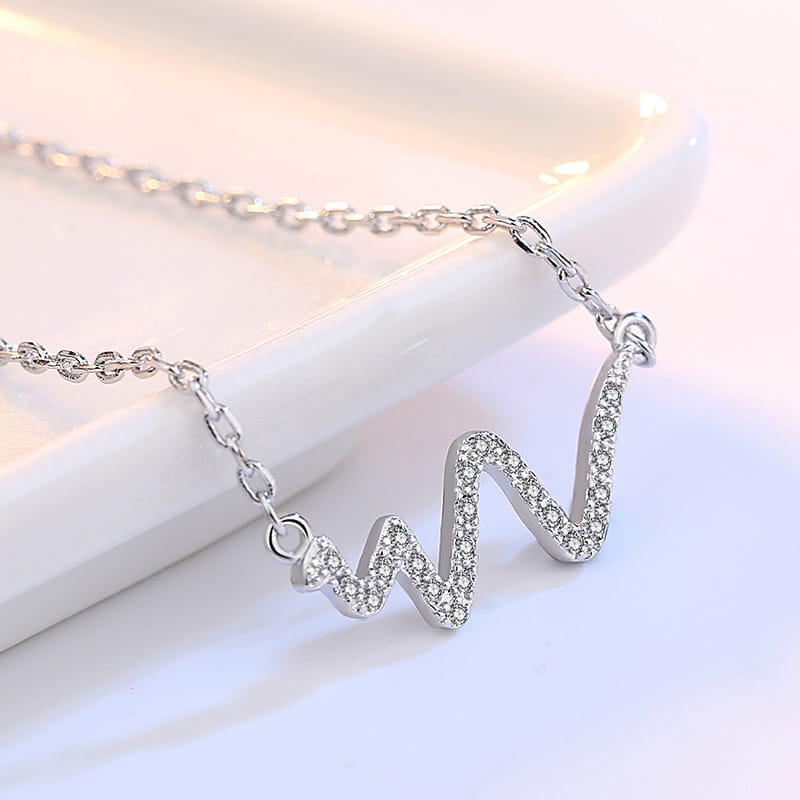 a delicate silver necklace korean featuring a heartbeat-shaped pendant with sparkling clear crystals along its wavy outline in the korean lightning necklace design