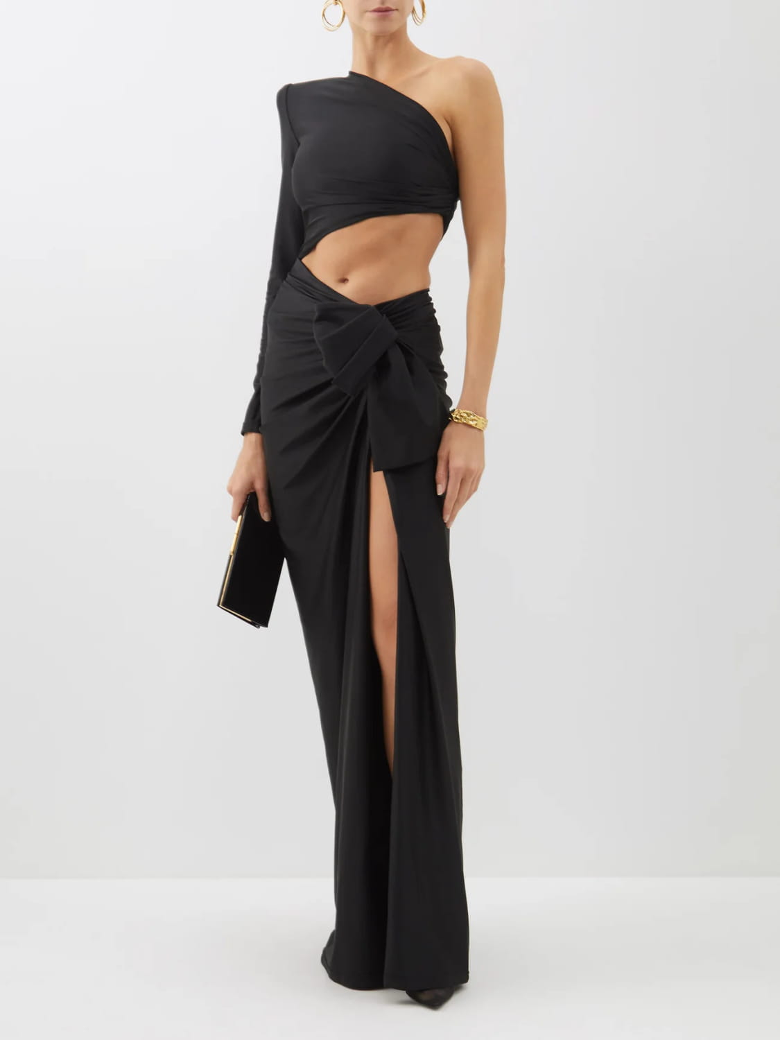 Black long sleeved hollow slit elastic shoulder dress featuring a one-shoulder draped gown style with a high slit and tied waistband.