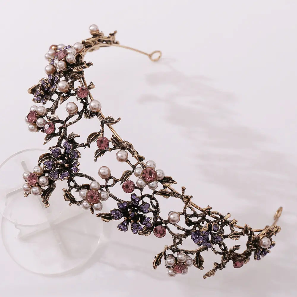 Floral black diamond pearl baroque bridal crown featuring an ornate vintage-style floral headpiece with intricate metalwork adorned with pink and purple crystals and pearl-like beads.