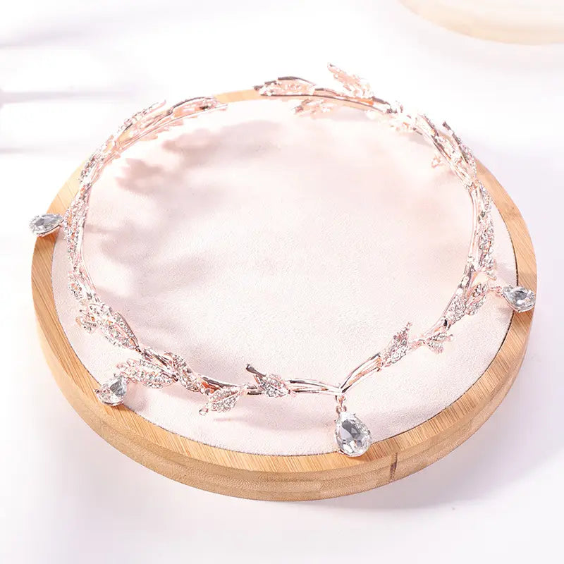 A delicate silver leaf golden crown headband adorned with sparkling clear crystals and dangling teardrop-shaped gems is designed as a crown headband wedding or headband wedding headdress.