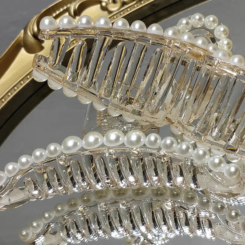 Clear acrylic pearl grab clip adorned with a row of lustrous white pearls and a rhinestone bow, designed as a gentle transparent grab clip for elegant hair styling.