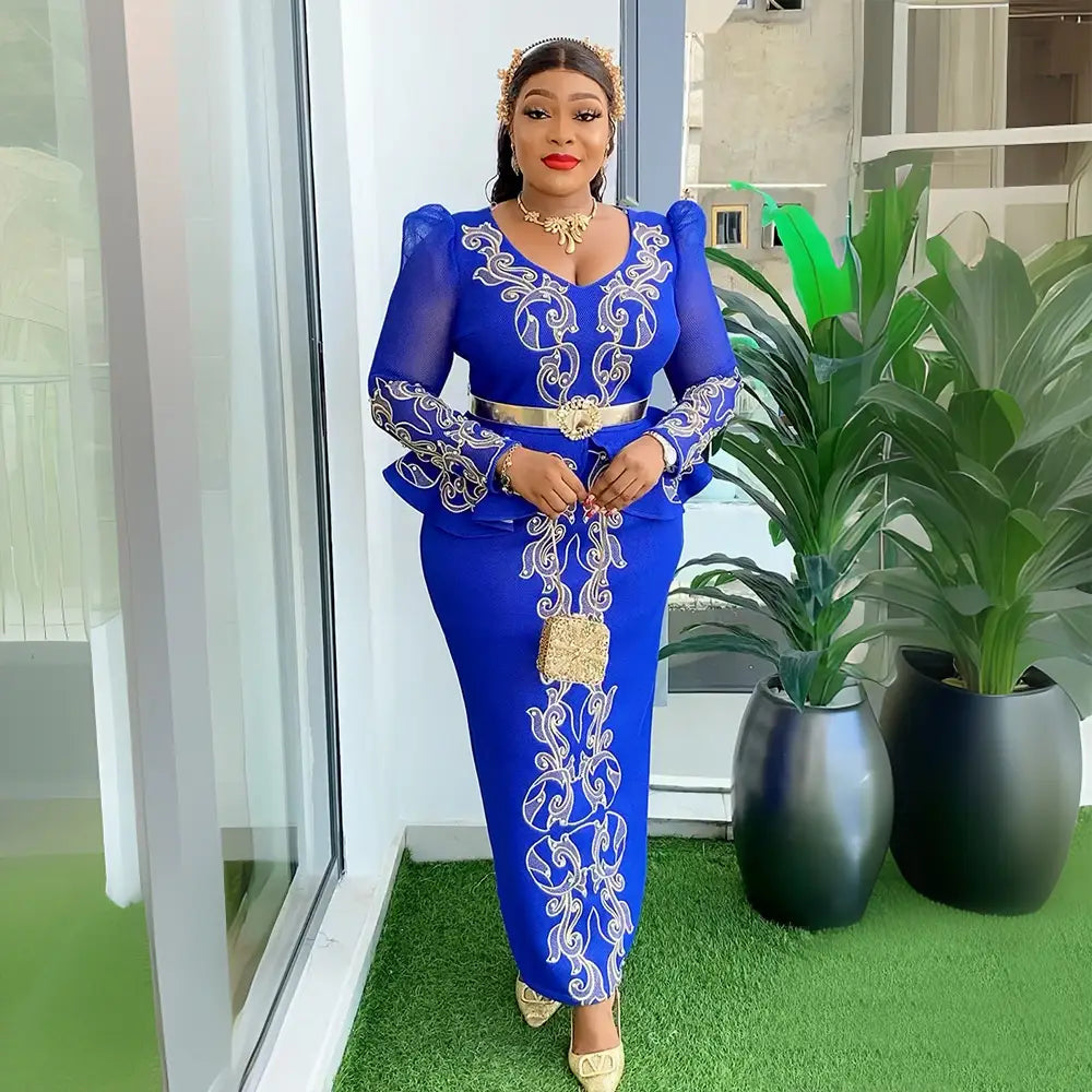 Luxury rhinestone beaded royal blue long-sleeved gown with intricate white and gold embroidery, fitted waist belt, and peplum detailing.