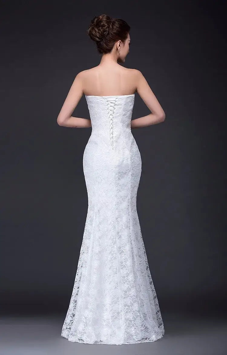 A white lace wedding dress with a mermaid-style long dress fuchsia inspired design featuring a strapless fitted bodice and back lacing.