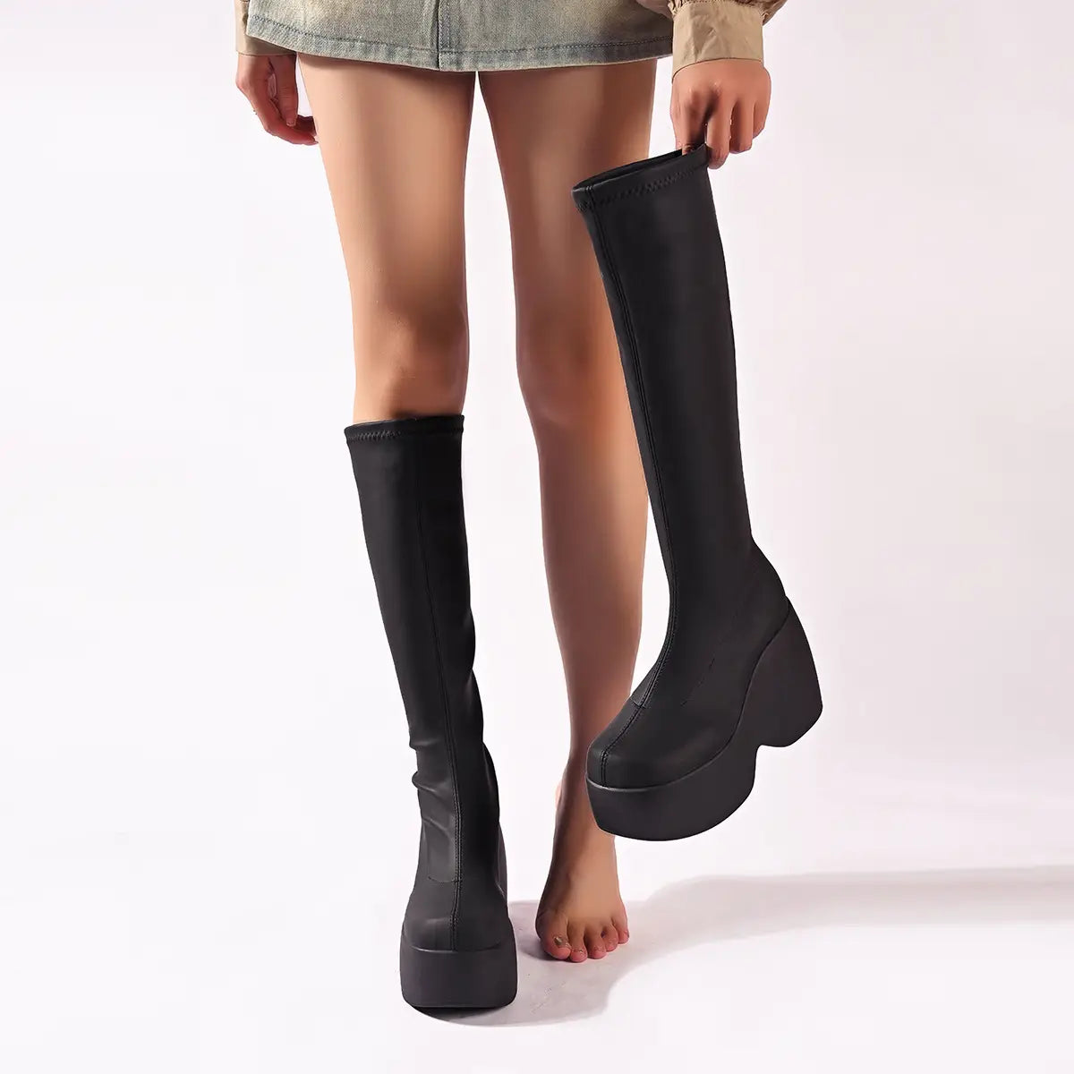 Black platform knee high elastic leather boots with a sleek stretchy fabric upper and a bold chunky sole designed for stylish wear.
