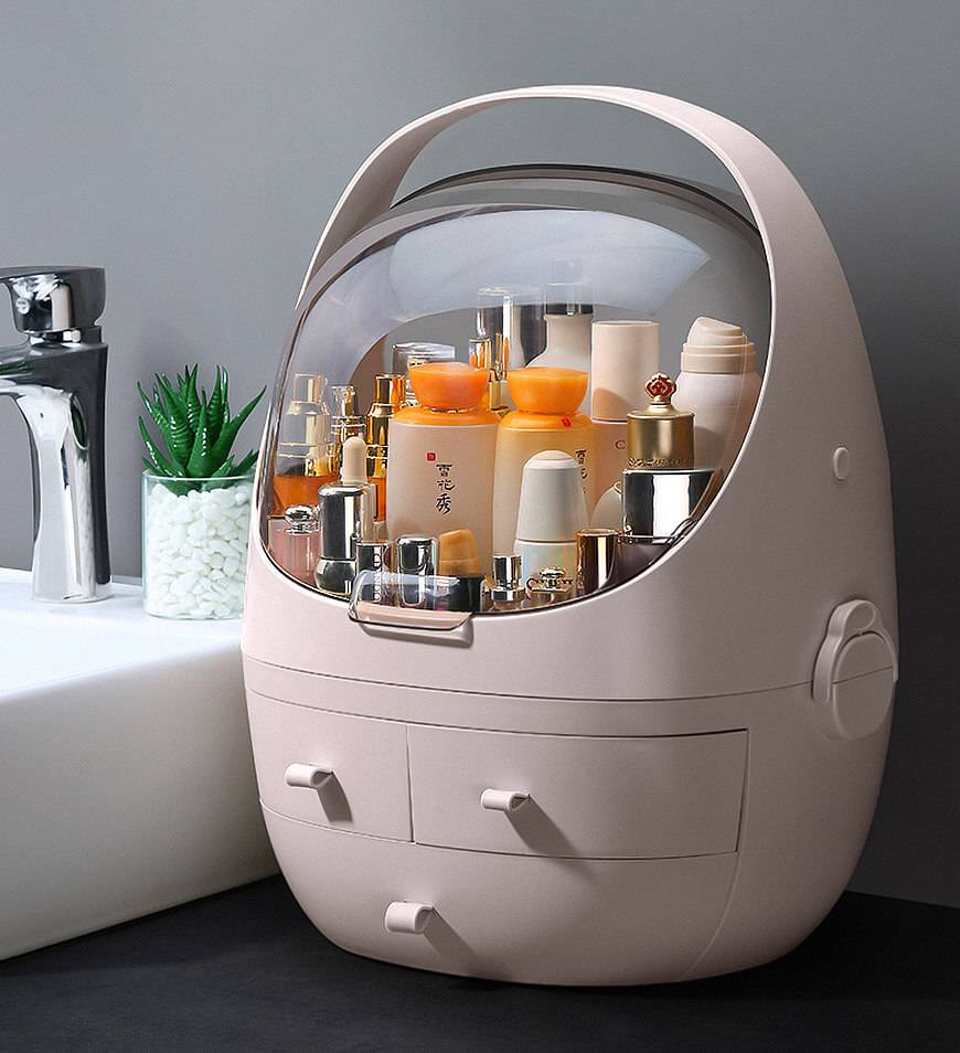 Pastel pink egg-shaped makeup organizer with a transparent dome lid and two drawers designed as a waterproof dust proof cosmetic storage solution.