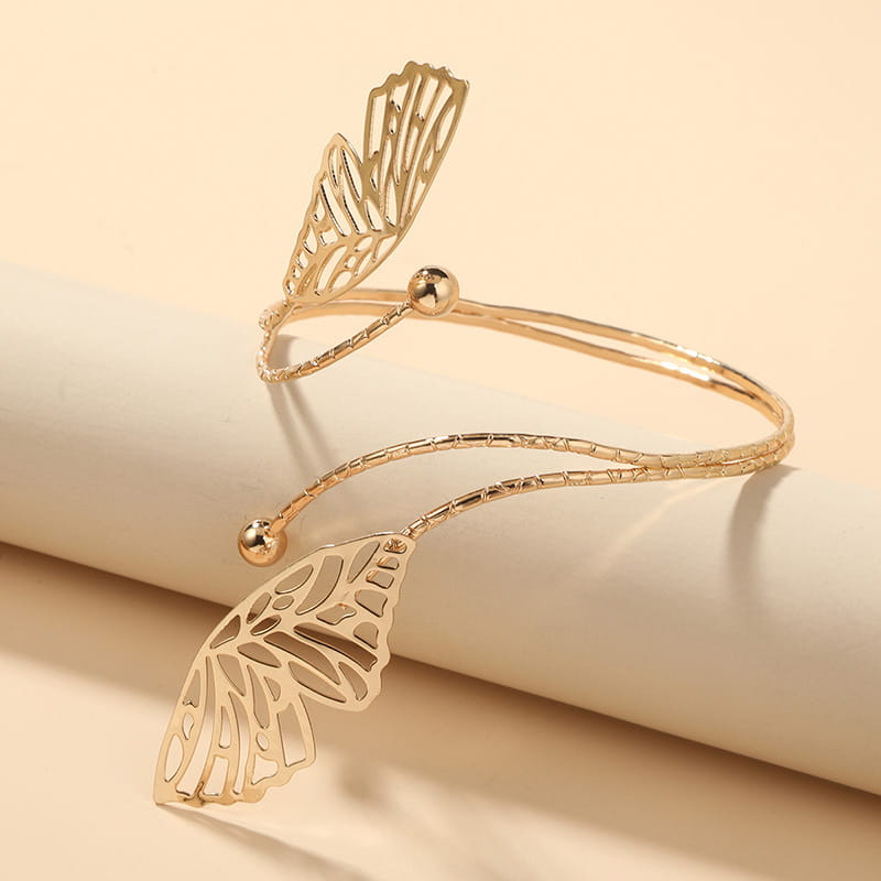 Gold-toned butterfly wing cuff bracelet with intricate cut-out detailing and textured band showcasing a fashion personality trend accessory.