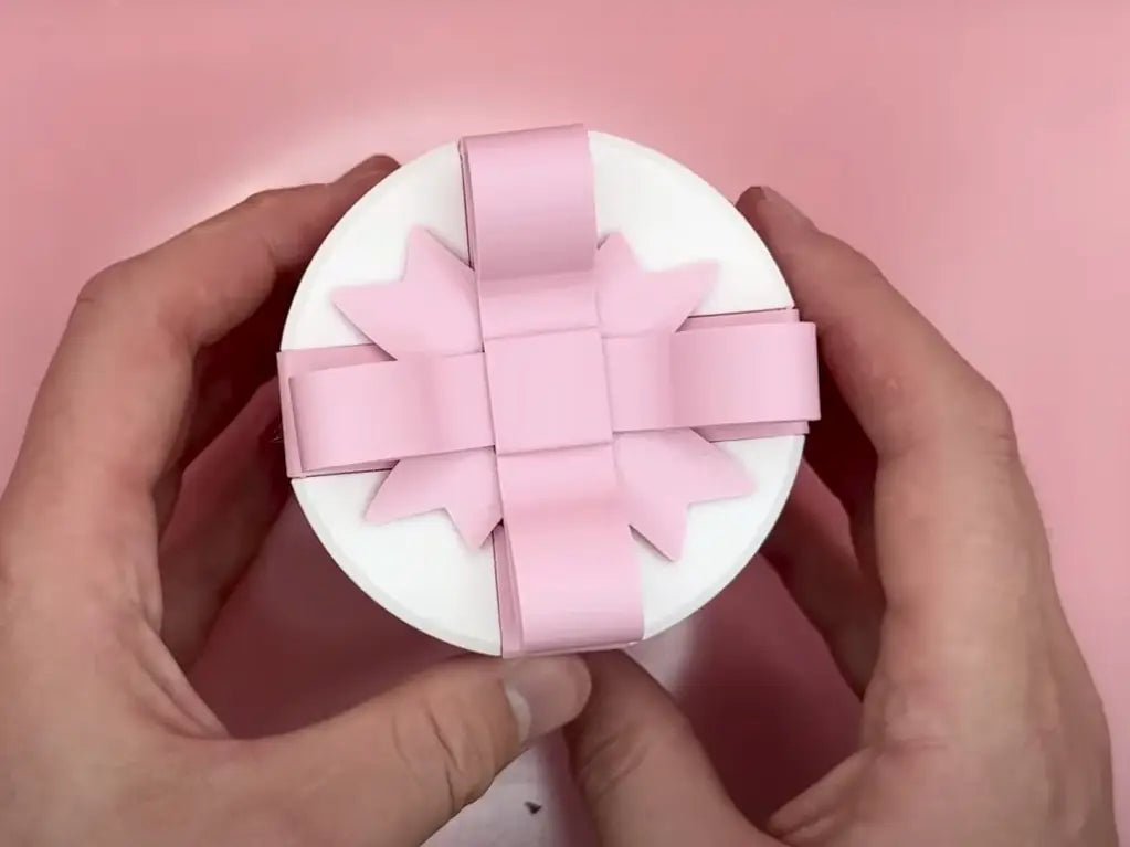 A white circular day gift box adorned with a delicate pink satin ribbon bow for valentine day gift.