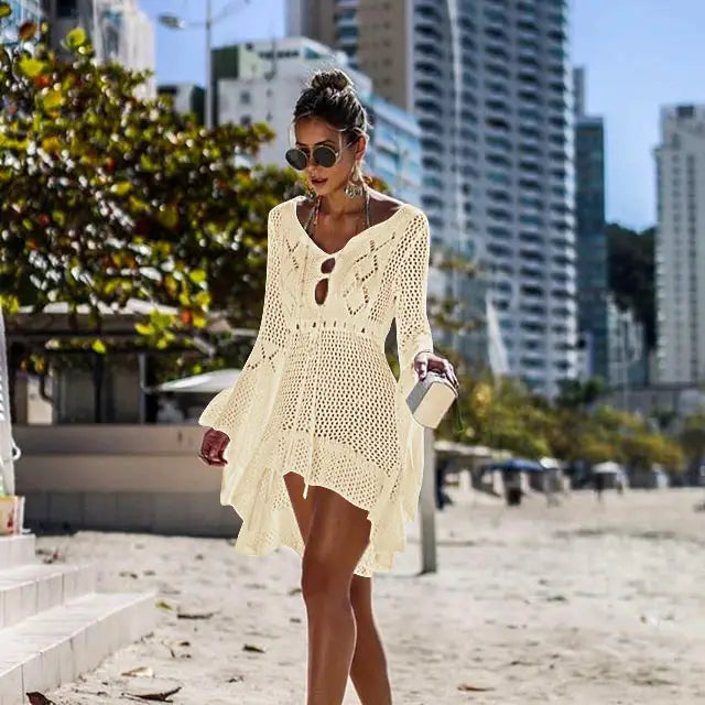 A creamy off-white long-sleeved crochet women swimsuit cover up dress with eyelet detailing and a flowing asymmetrical hem perfect for bikini women swimsuit use.