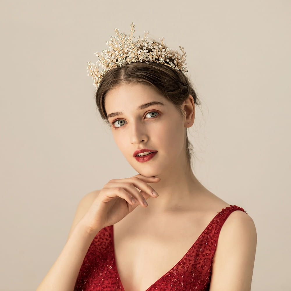 A delicate gold-toned bridal tiara adorned with sparkling crystals and intricate floral designs featuring rice beads rhinestone accents in rhinestone bridal headwear.
