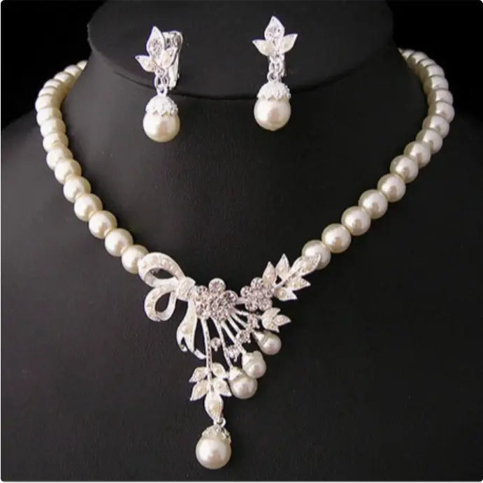 Elegant pearl necklace with a silver-toned floral and bow pendant accented by sparkling crystals, perfect bridal ornaments for wedding ladies and complementing wedding gowns.
