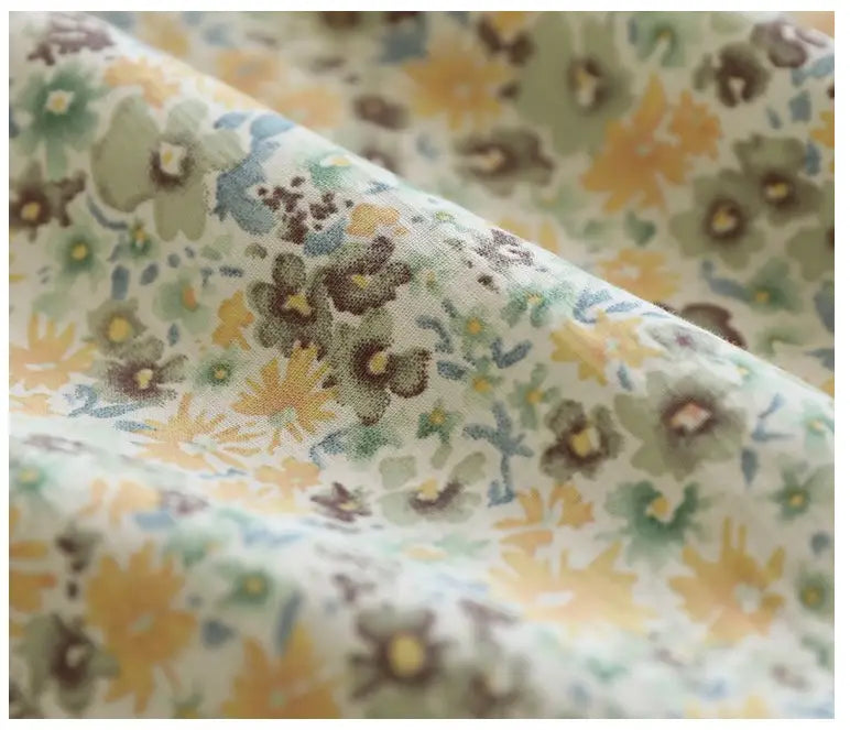 artistic floral washed cotton midi skirt featuring soft cream-colored fabric with a delicate floral pattern in muted yellows greens and browns
