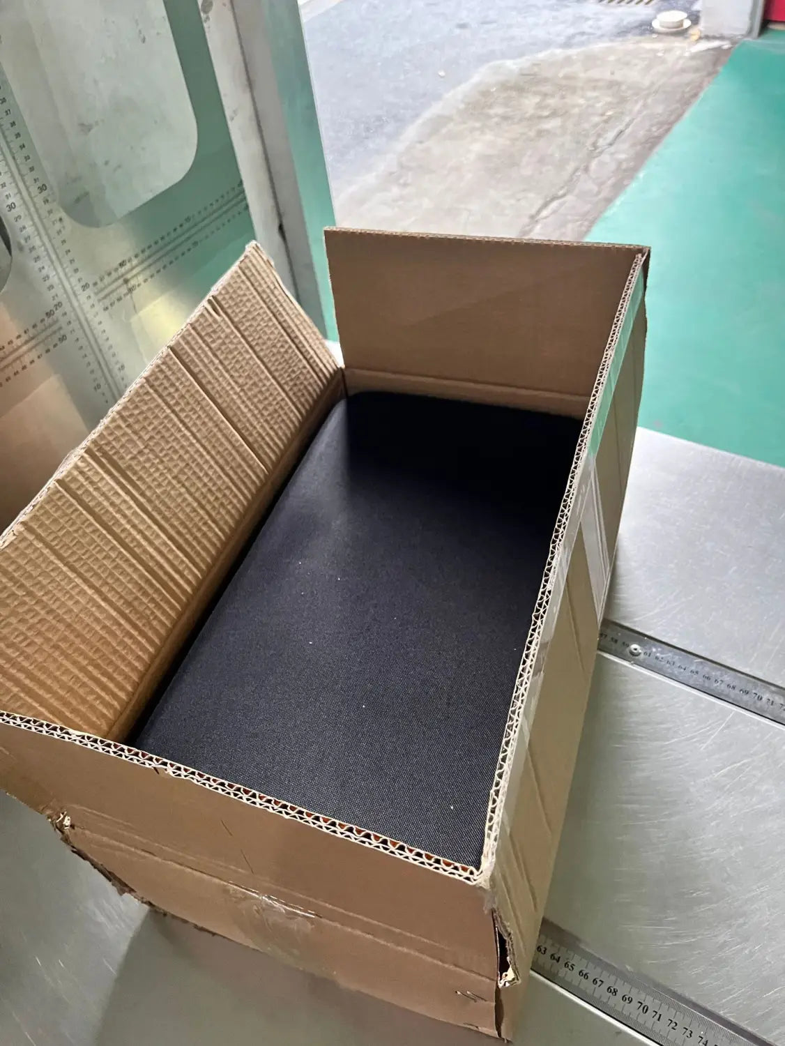 a black textured foam pad inside an open brown cardboard box for a multifunctional car wash high pressure water gun kit