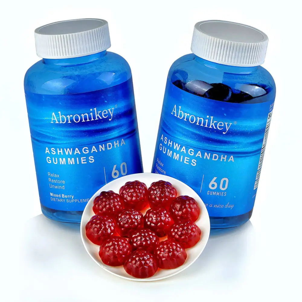 Two translucent blue abronikey ashwagandha vitamin d gummy bottles with white caps beside red mixed berry gummies on a plate