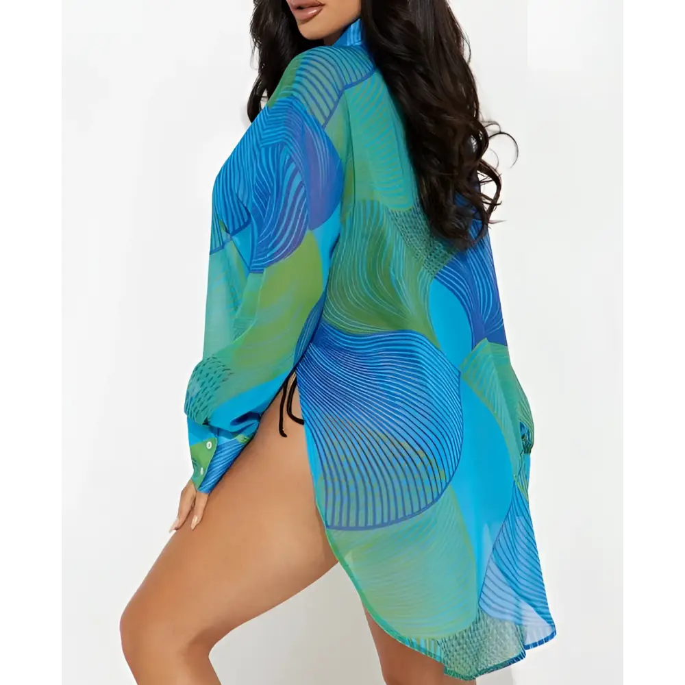 A vibrant blue and green sheer flowing beach cover-up with abstract wave-like patterns complements a printed bikini blouse