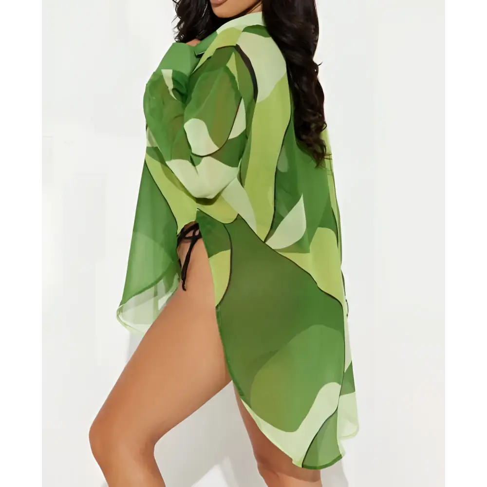 A sheer green camouflage beach cover-up with side tie paired with an abstract pink and orange printed bikini blouse