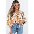 A woman wears a vibrant fashion colorblock printed chiffon shirt women with abstract floral orange and pink patterns