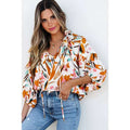 A woman wearing a fashion colorblock printed chiffon shirt women with abstract floral orange pink and green hues