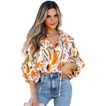 A woman wearing a fashion colorblock printed chiffon shirt women with an abstract floral pattern in orange pink and teal hues
