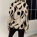 Beige abstract printed notched collar shirt long sleeve with bold black geometric patterns and a formal design