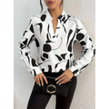 Black crocodile-textured clutch with silver circular handle beside abstract printed notched collar shirt long sleeve