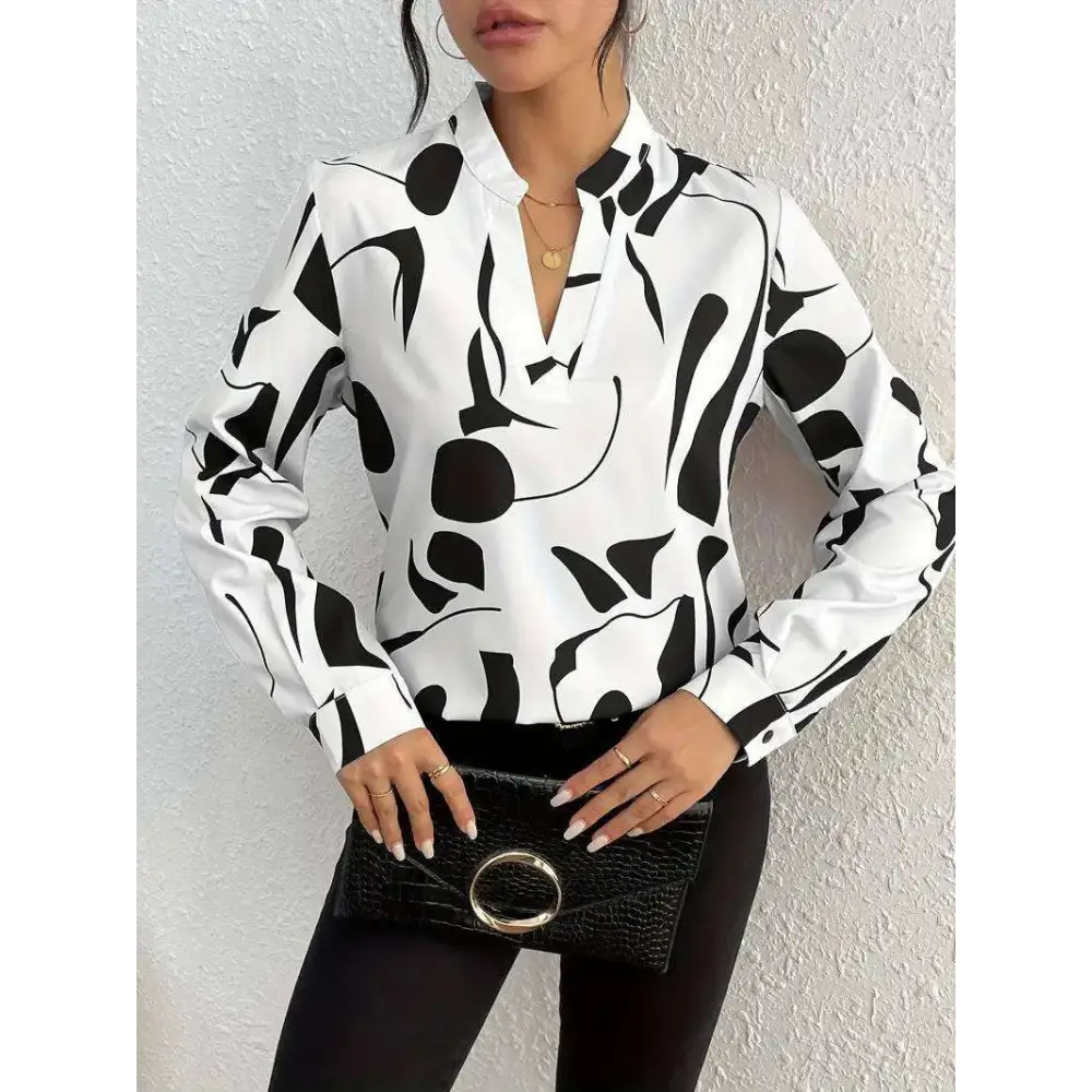 Black crocodile-textured clutch with silver circular handle beside abstract printed notched collar shirt long sleeve
