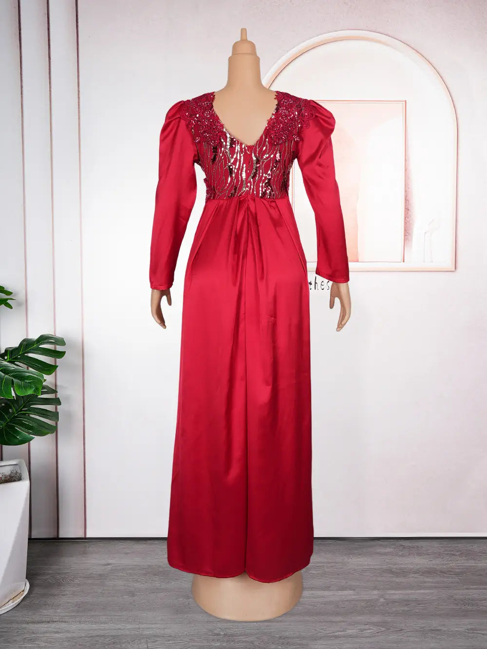 A vibrant red plus size long sleeve sequined evening dress with a satin skirt and a sequined bodice displayed on a mannequin.