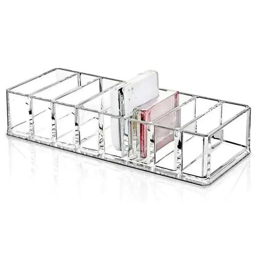 Clear acrylic makeup organizer with compartments holding multiple items including white phone and pink card