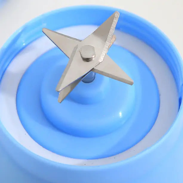 Silver star-shaped blender blade with sharp edges mounted on a blue plastic base of an electric fruit juicer for portable USB rechargeable mixing