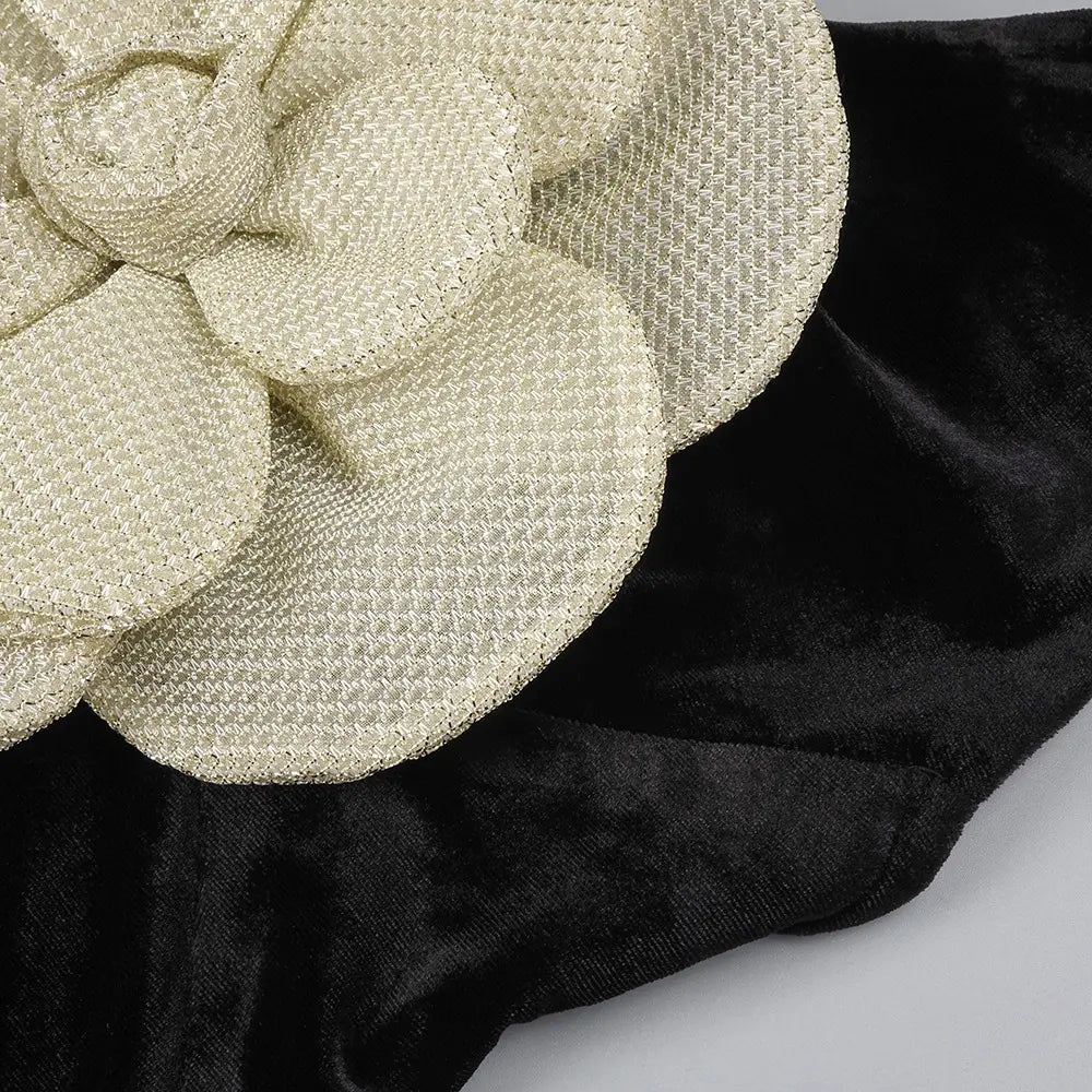 a delicate cream-colored woven flower accessory with textured shimmering fabric on the back side of a black camisole backless slim fit velvet floral gown