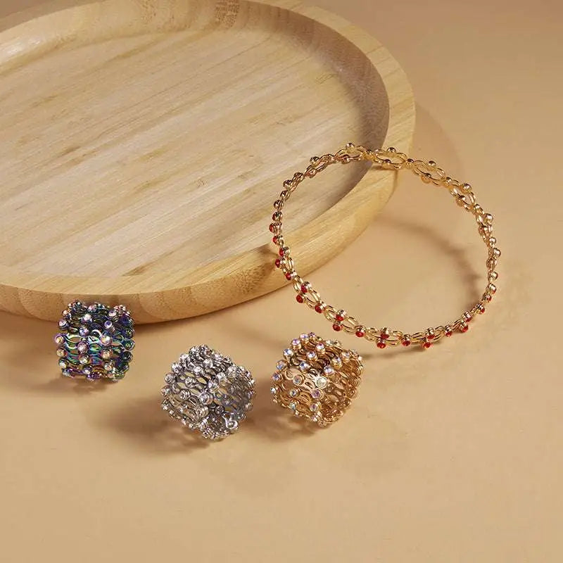 Gold-toned adjustable rhinestone bracelet with intricate chain links and red gemstones in a fashion rings set