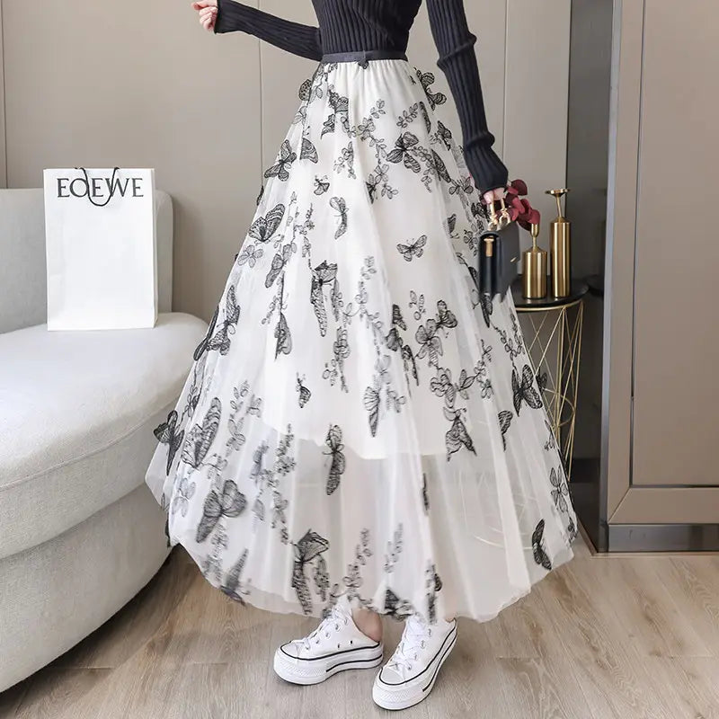 a flowing white embroidered bow lace mesh skirt with intricate black butterfly embroidery paired with a ribbed black top and white platform sneakers