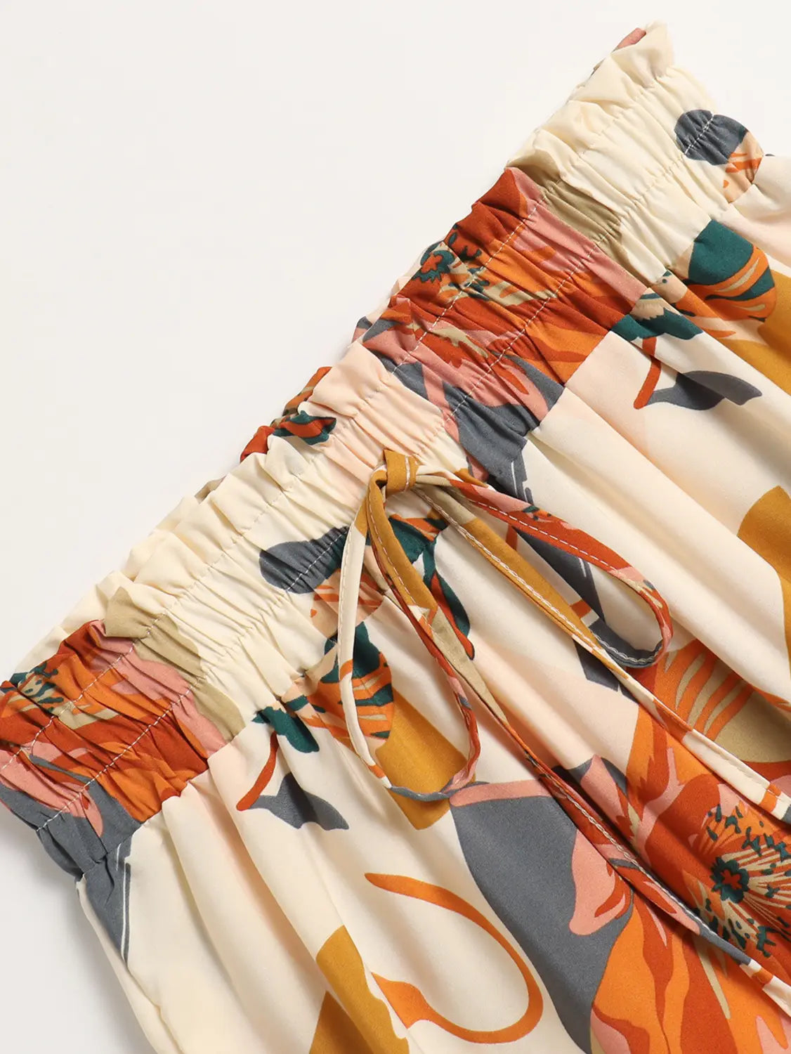 Cream tiered pleated floral print skirt in cream color with vibrant orange gray and teal abstract floral print and floral print elastic waistband.