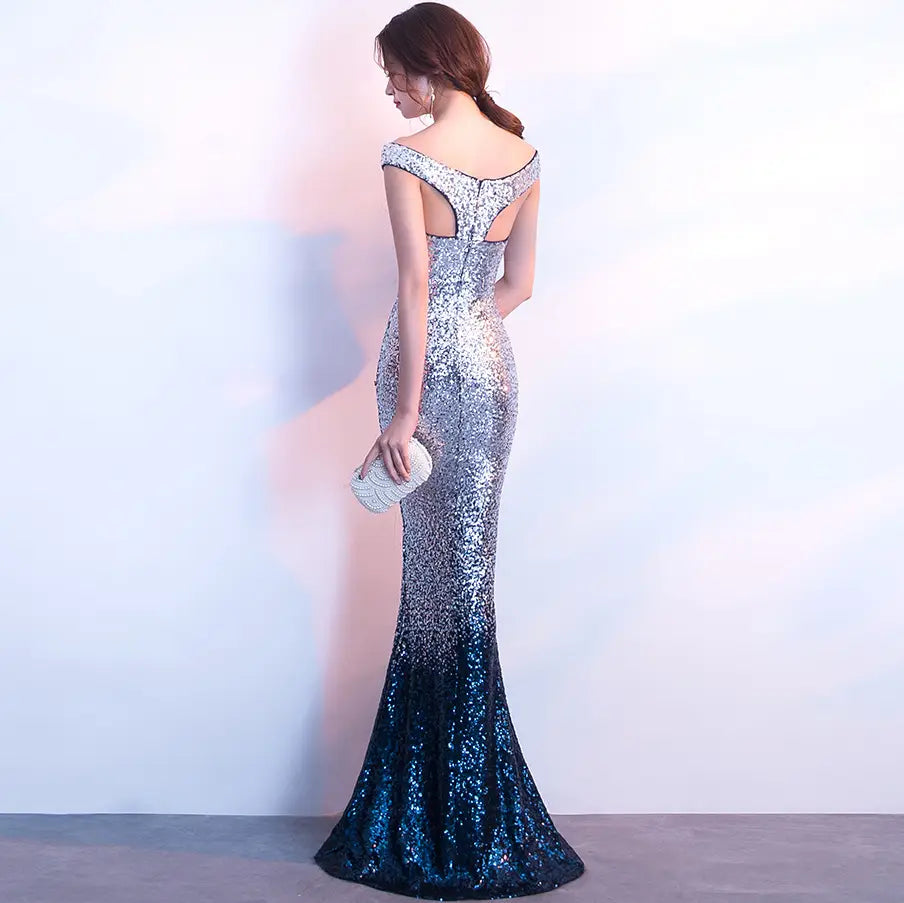 a shimmering silver to blue sequined mermaid gown with an off the shoulder back and a fitted silhouette designed as a long slim fit fashion host gown