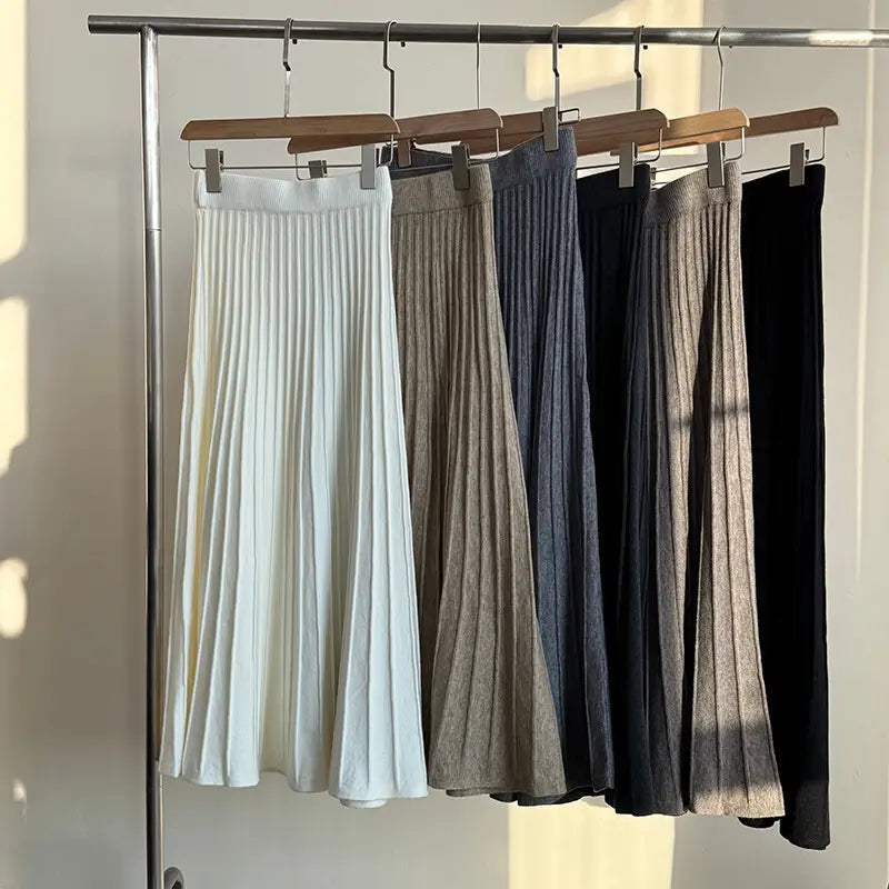 a collection of five korean elastic waist knitted pleated midi skirts in white beige navy blue charcoal gray and black showcasing neutral tones and pleated design