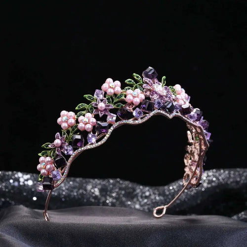 A wedding bridal tiara with alloy crystal flowers pink pearls purple crystals and green leaf accents on rose gold base