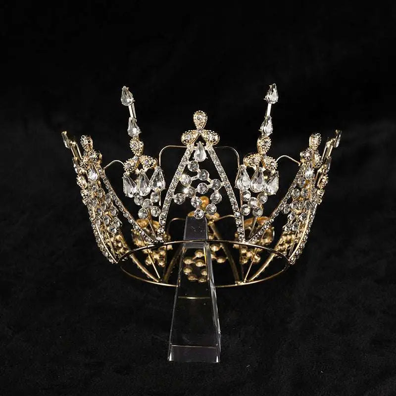 A sparkling gold alloy electroplate crown korean style with clear crystals and intricate leaf detailing on a transparent stand