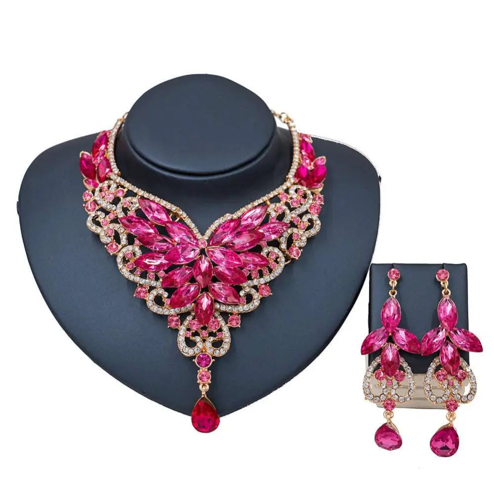 A vibrant fuchsia and rose gold rhinestone color exaggerated bride necklace set with intricate floral designs and teardrop stones