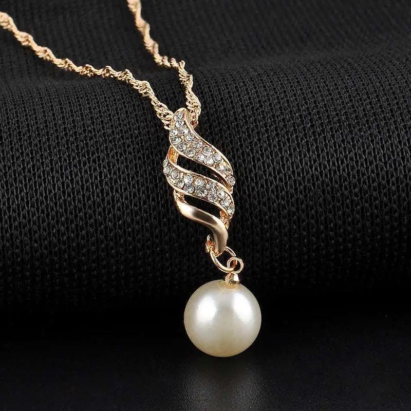 Gold-toned american wedding jewelry necklace with twisted crystal pendant and matching pearl drop earrings on black mannequin