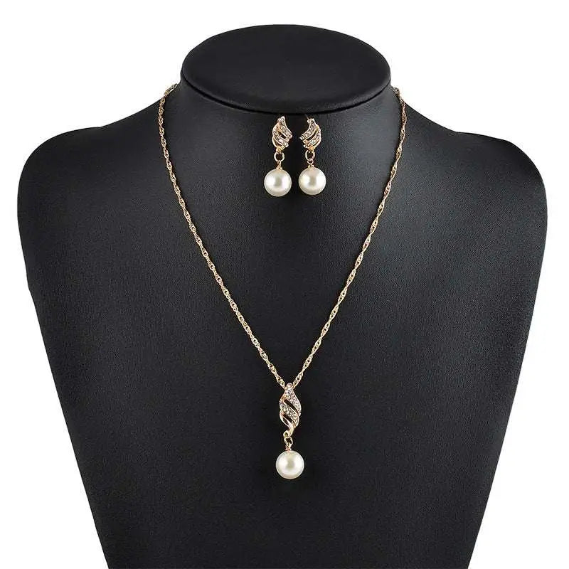 Gold-toned american wedding jewelry necklace with twisted crystal pendant and matching pearl drop earrings on black mannequin
