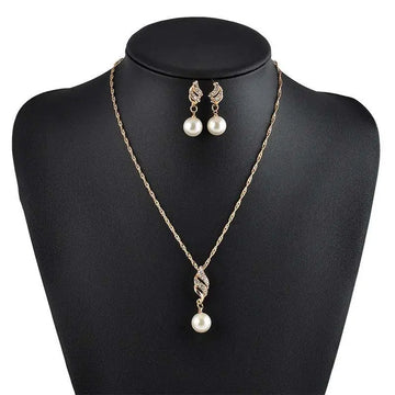 Gold-toned american wedding jewelry necklace with twisted crystal pendant and matching pearl drop earrings on black mannequin
